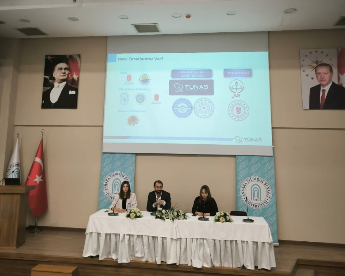 TÜNAŞ'dan gelen Zeynep Hülya Yıldırım, Meryem Erat Şekerci ve Memet Salih Timur'un sahnede oturmuş şekilde sunum yaparken çekilen fotoğrafı